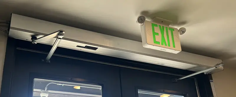 Door arms and hardware mounted above a commercial double door